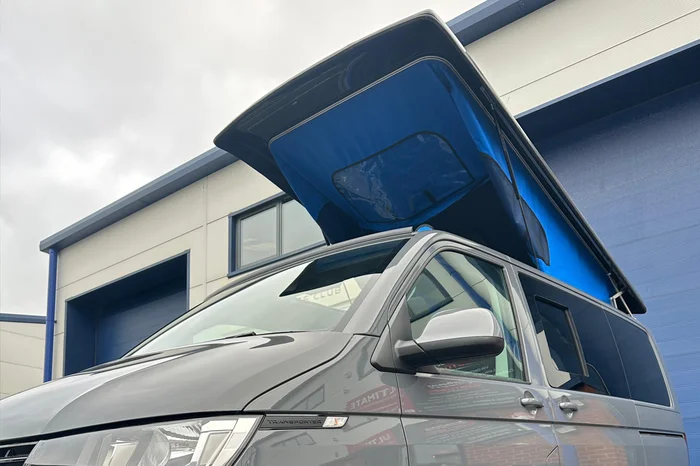 Silver VW T5 with red pop top roof